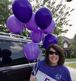 Teacher holding purple balloons 